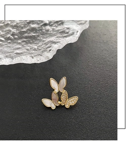 Macro detail of three golden butterfly brooches with white shell and inlaid crystals