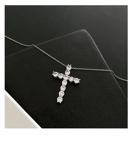 Close-up of silver cross pendant necklace with clear round brilliant-cut gemstones