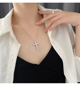 Close-up of a silver cross pendant necklace with sparkling cubic zirconia on a model