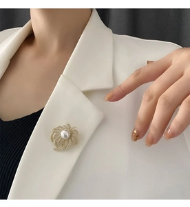 Detailed view of an elegant gold flower brooch featuring micro-set zircons and a large pearl