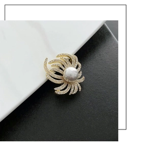 Detail of luxury gold lapel pin featuring a white pearl and zircon-encrusted feathers