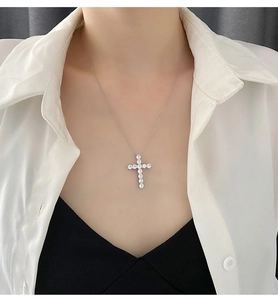 Close-up of sparkling cross pendant necklace with round-cut gemstones on woman neck