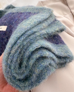 Close-up of blue-purple mohair knit fabric texture with fluffy yarn and woven label
