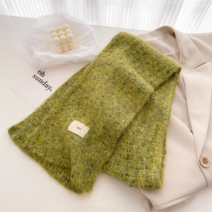 Close-up of green wool blend knit scarf showing textured yarn and woven ins label