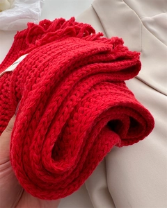 Macro shot of red knit wool scarf showing chunky texture and fringe tassel detail