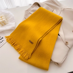 Detail of ginger yellow knitted scarf with tassels and a leather Hand Made label