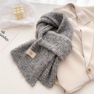 Close-up of gray wool-blend knit scarf showing thick texture and minimalist ins tag detail
