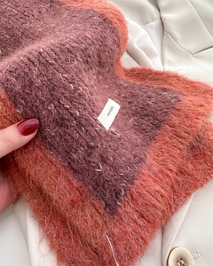 Detail of color-block knit scarf showing hairy texture and brand label on white blazer