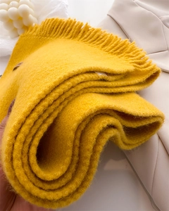 Close-up of ginger yellow knitted scarf featuring soft fringe and thick warm texture