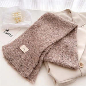 Close-up of brown wool knit scarf with speckled texture and minimalist label detail