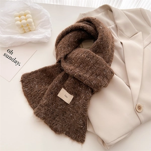 Detail of coffee brown wool knit scarf texture with a small patch label and soft texture