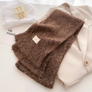 Detail of wool blend knit scarf in brown with white dots and fabric label on a blazer