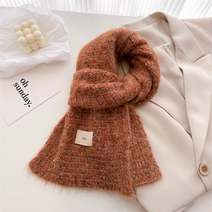 Detail of red-brown knit wool scarf with colorful specks and ins label tag