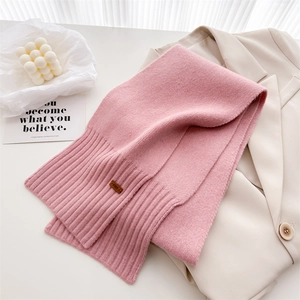 Detailansicht eines rosa Strickschals aus Wolle mit Rippstrick und Leder-Markenlabel
