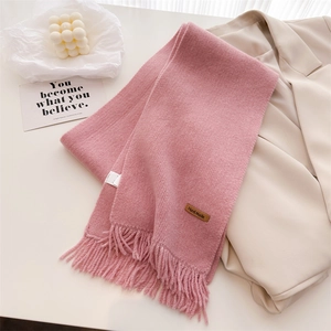 Detail of pink knitted scarf featuring fine texture, soft tassels and handmade leather label
