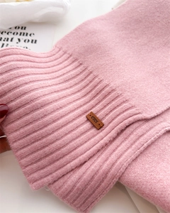 Nahaufnahme von rosa Strickschal mit Rippenstruktur und braunem Lederetikett-Detail