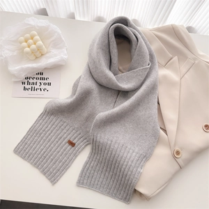 Detailaufnahme eines weichen grauen Strickschals mit Rippenrand und Lederetikett