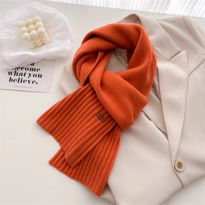 Weicher warmer orangefarbener Strickschal aus Wolle auf einem beigen Blazer gestylt