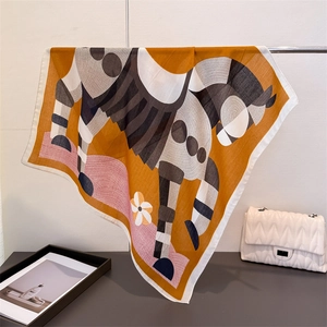 Detail showing orange horse print silk scarf with abstract patterns hung over a white bag