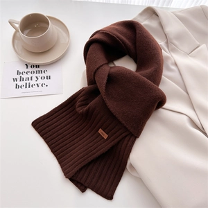 Nahaufnahme des schokobraunen Strickschals mit ever-Label und gemütlicher Dekoration