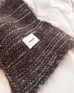 Détail d'écharpe en maille marron foncé avec étiquette Bonogeed sur texture mohair
