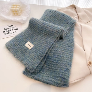 Détail d'une écharpe en maille de laine bleu sarcelle avec étiquette et texture peluche