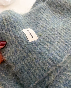 Gros plan d'une écharpe en tricot violet montrant la texture douce et l'étiquette