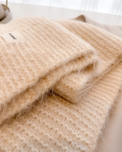 Détail d'une écharpe en laine tricotée crème douce avec étiquette de marque en tissu