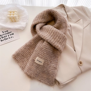 Gros plan d'une écharpe en maille de laine beige avec étiquette de marque et texture douce