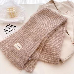 Détail d'une écharpe en laine tricotée beige avec étiquette et texture mohair douce