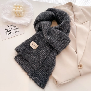 Texture détaillée d'une écharpe en maille gris foncé avec étiquette sur blazer beige