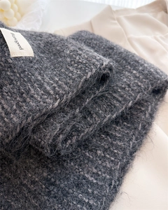 Gros plan sur une écharpe en laine gris foncé avec texture pelucheuse et étiquette chic