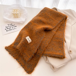 Détail d'une écharpe en maille caramel avec étiquette blanche et texture laineuse douce