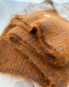 Gros plan sur l'écharpe en maille de laine caramel montrant la texture douce du mohair