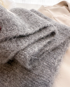 Gros plan d'une écharpe en maille pelucheuse grise montrant la texture douce