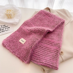 Détail d'une écharpe en maille mohair rose et grise sur un blazer beige avec décorations
