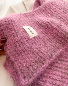Gros plan détaillé sur l'écharpe en laine rose à grosse maille avec étiquette de marque