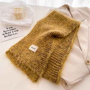 Gros plan d'une écharpe en maille jaune doux avec une étiquette de marque blanche tissée