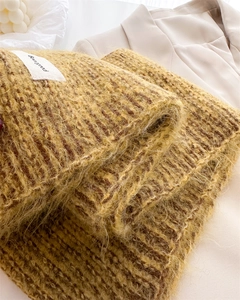 Détails de la texture d'une écharpe en laine tricotée jaune gingembre avec étiquette