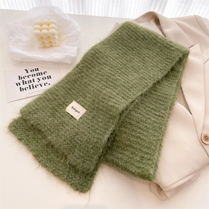 Détail d'une écharpe en maille de laine verte avec texture douce et étiquette de marque