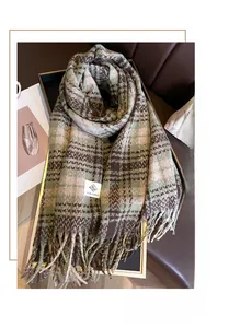 Close-up of checkered autumn scarf with fringe details and woven label on wool fabric
