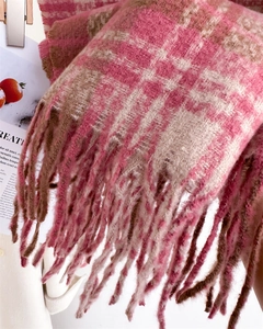 Close-up of pink plaid knit scarf featuring thick yarn texture and long fringe details