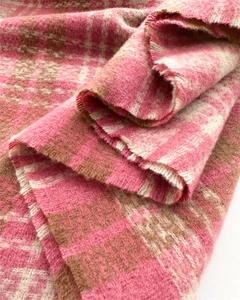 Macro shot of pink and beige plaid shawl showing soft brushed cashmere-like texture and fringe