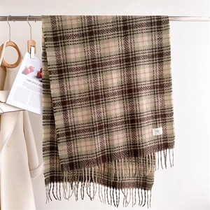 Detail of plaid scarf with olive green, coffee and beige tassels hanging on metal rod
