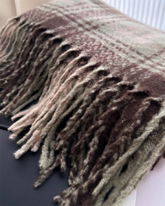 Close-up of thick plaid scarf texture with soft tassels in green and brown