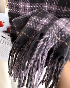 Detail of purple and black plaid knit scarf with long tassels and thick wool-like texture