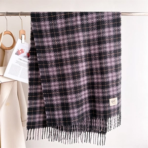 Close-up of thick plaid scarf featuring purple tassels and minimalist brand label