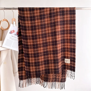 Detail of checkered warm scarf featuring dark brown tassels and soft textured knit yarn