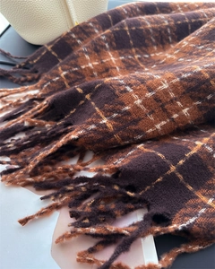 Detail of soft brown and orange plaid scarf texture with long fringe tassels