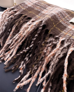 Close-up of thick plaid scarf with long fringe tassels in dark coffee and ginger yellow